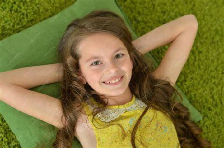 Portrait of girl lying on bed with mothers feet Stock Photo Dissolve